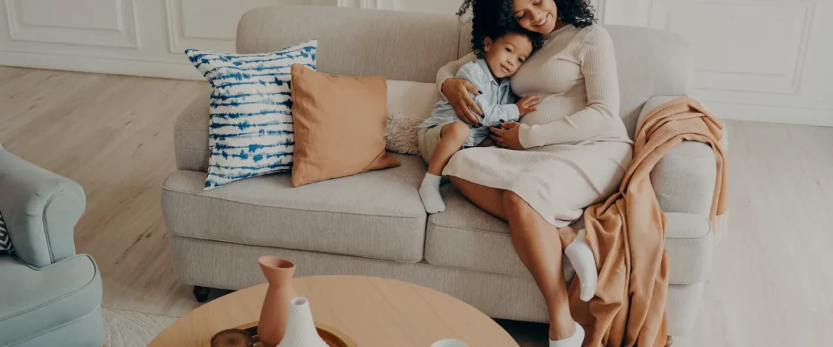 mother holding her small son on a sofa in a bright room