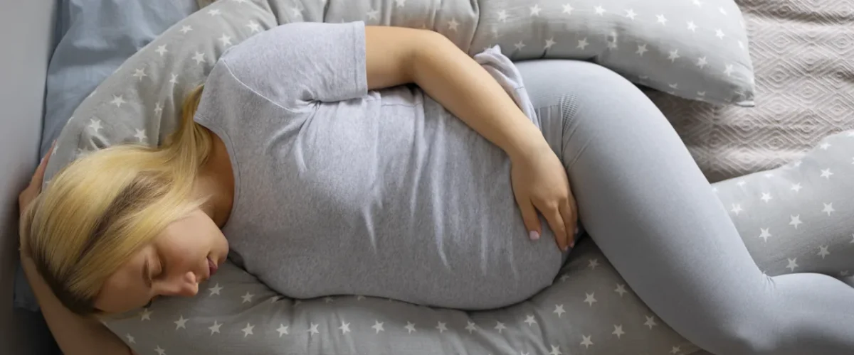 a pregnant woman sleeping on her side hugging a body pillow