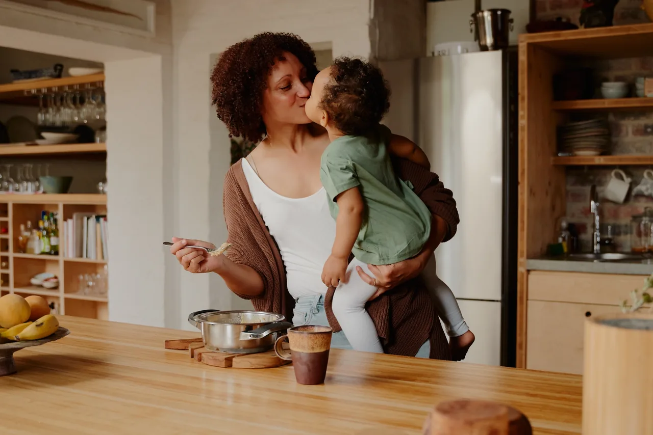 une mère embrasse son tout-petit tout en cuisinant
