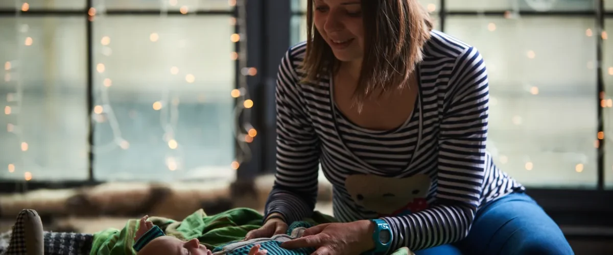 mother tending her baby on a blanket by a window
