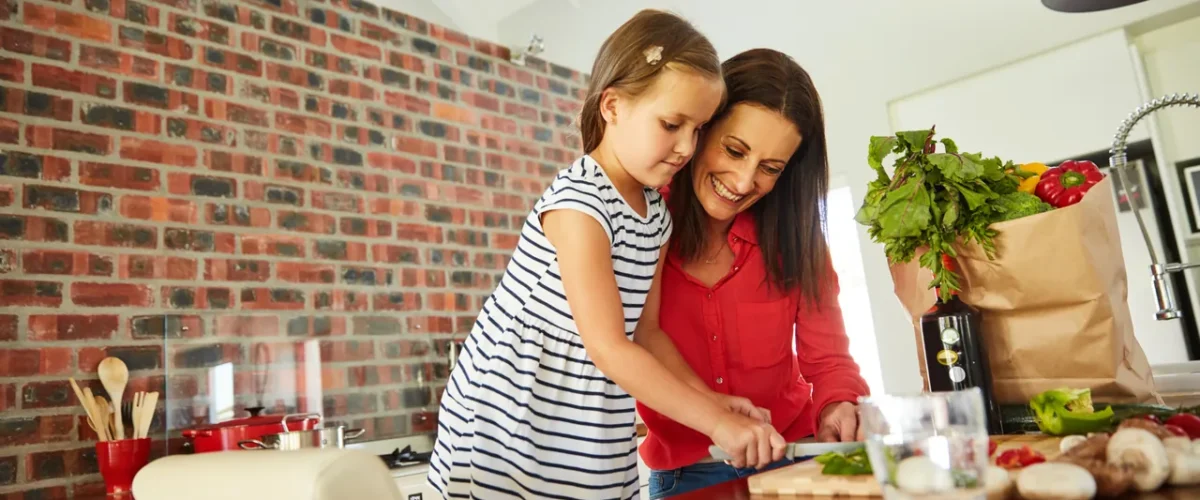 mother and daughter preparing vegetables in a brick walled kitchen
