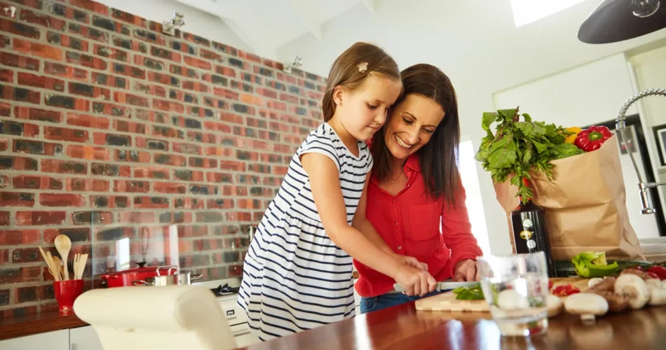 mother and daughter preparing vegetables in a brick walled kitchen