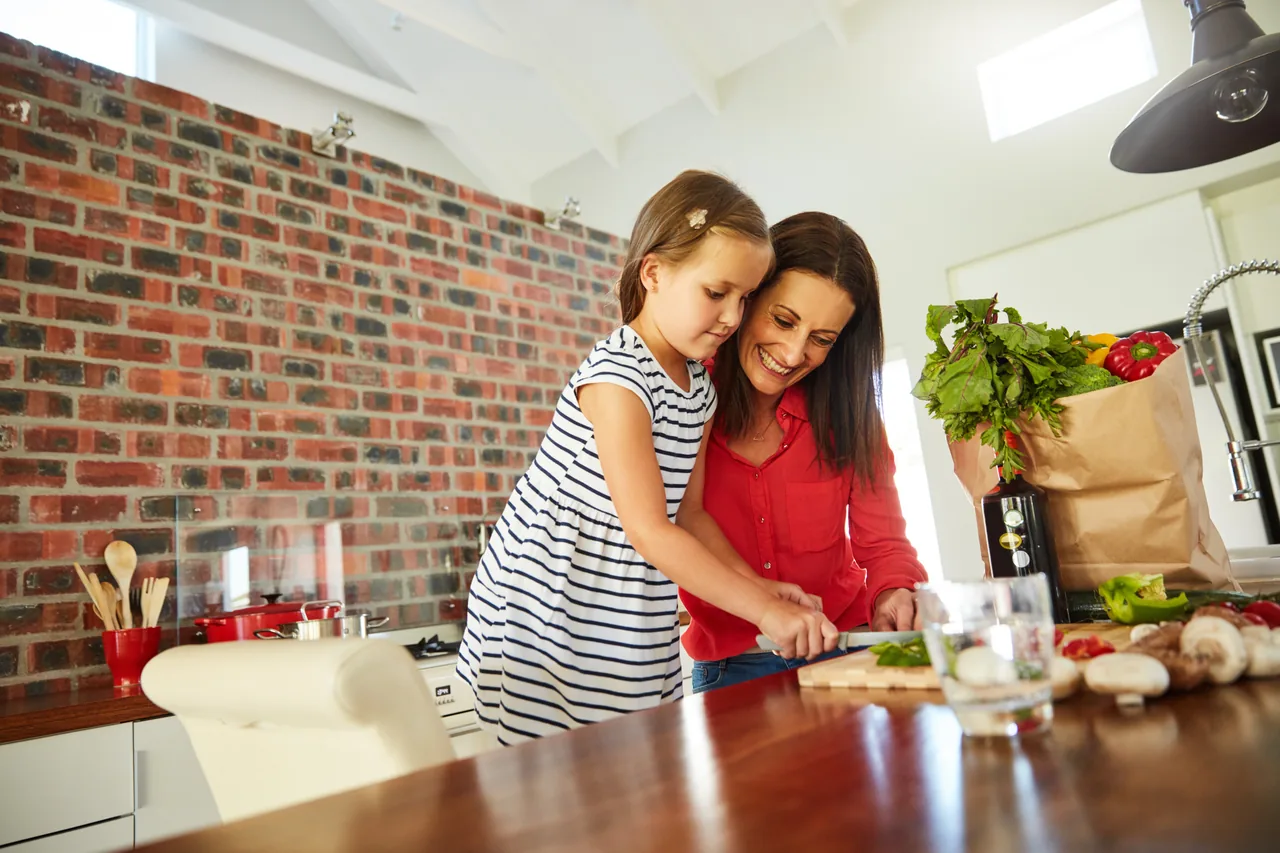 une mère et sa fille préparent des légumes dans une cuisine aux murs de brique