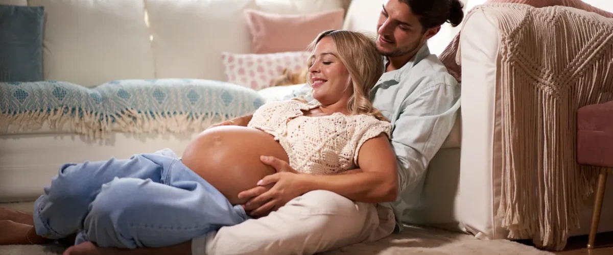expecting couple sitting among cushions on the floor