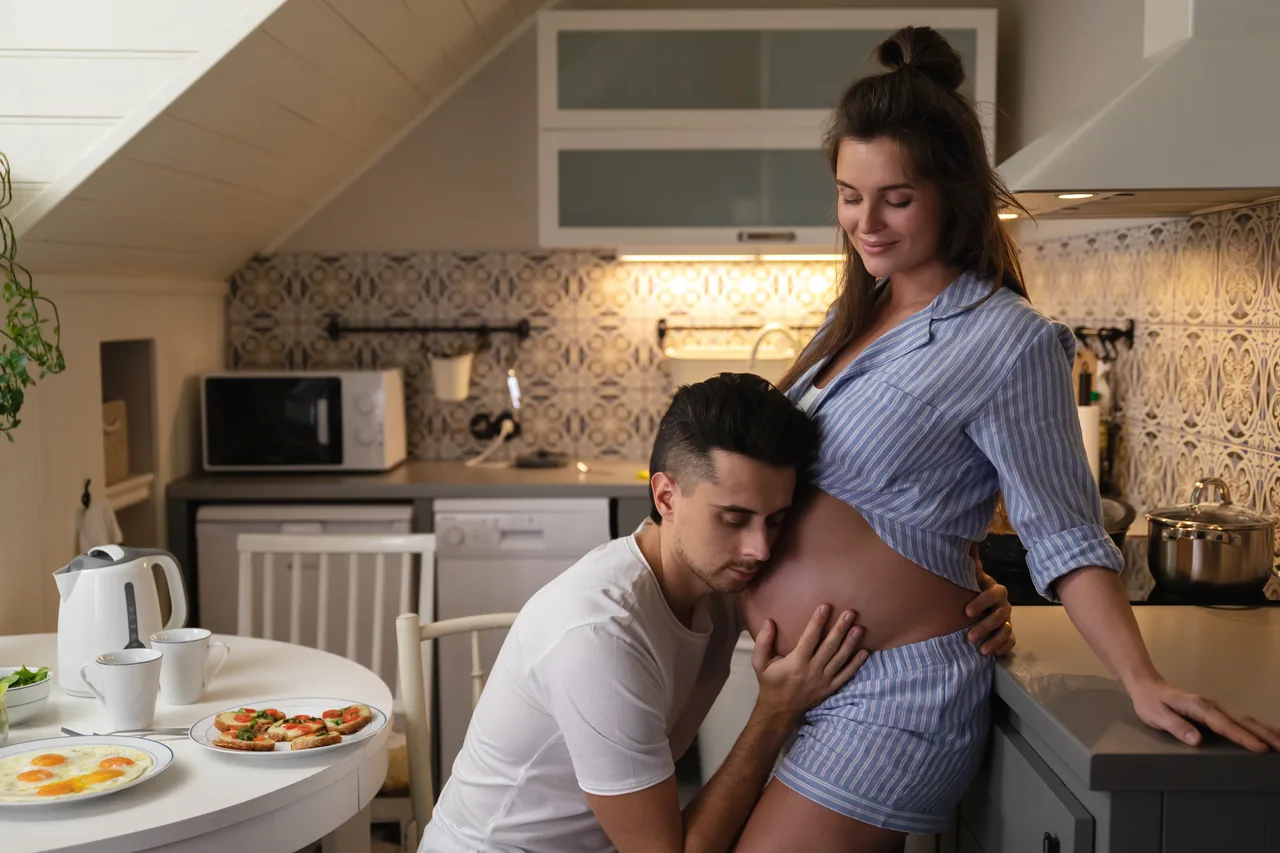 o companheiro se inclina para a barriga na cozinha no café da manhã