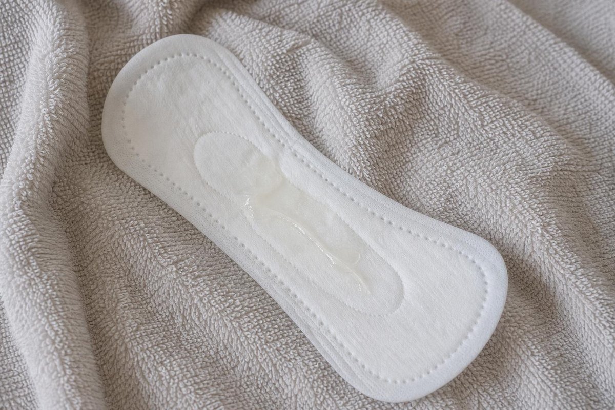 Weiße Slipeinlage auf einem weichen hellen Handtuch mit einem kleinen klaren, glänzenden Feuchtigkeitsfleck in der Mitte